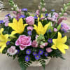 Basket arrangement with pink roses, yellow lilies, and purple daisies