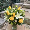 Yellow roses and white lilies arranged in a clear glass vase