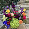 Colorful mixed flower arrangement in a glass vase with roses, hydrangeas, and dahlias