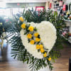 Heart-shaped white floral spray with yellow roses and palm fronds