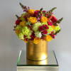 Bright mixed bouquet in a gold hatbox with yellow and pink flowers