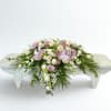 White and blush floral arrangement on a low white bench