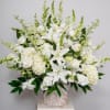 Large all-white arrangement of lilies, roses, hydrangeas, and snapdragons in a white woven basket.