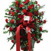 Tall standing spray of red roses and carnations with a red ribbon on an easel