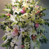 Tall white and pink standing spray of lilies, daisies, and roses with flowing white ribbon