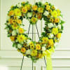 Heart-shaped standing wreath of yellow and white flowers on a metal easel with a yellow bow.