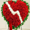 Standing red carnation heart wreath with white zigzag stripe and greenery border on an easel