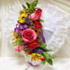 Bright pink and red floral spray with yellow accents on a white lace heart pillow and purple ribbon.