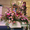 Casket piece with pink roses, pink carnations, and purple stock.