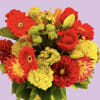 Bright mixed bouquet of red and yellow flowers in a glass vase
