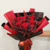 Bouquet of red roses wrapped in black and red paper with a ribbon