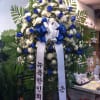 Large standing floral wreath with blue and white flowers and ribbon