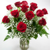 Red roses arranged in a clear glass vase with white baby's breath