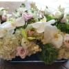 Low floral centerpiece with white orchids, hydrangeas, and pale pink blooms