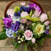 Basket of pink, purple, and blue flowers with roses and lilies