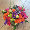 Colorful mixed bouquet in a clear glass vase with roses and gerbera daisies