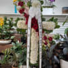 Tall standing floral wreath with red roses, white chrysanthemums, and orchids