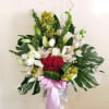 Large floral arrangement with red roses, white orchids, and lilies in a pedestal vase