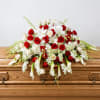 Red and white floral spray on a wooden casket