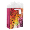 Decorative gift bag with a colorful floral print and white tissue paper