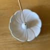 White ceramic flower-shaped incense holder on a wooden table