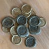 Stack of floral-patterned wax seals in gold and dark gray