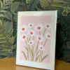 Framed print of white daisies with red centers on a pink background