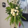 White roses and hydrangeas in a tall green standing arrangement