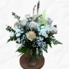 White roses and lilies arranged in a glass vase with greenery