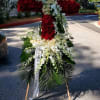 Tall standing cross of red and white flowers on an easel with cascading white blooms