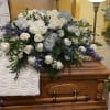 A beautiful white casket spray with a pop of blue