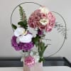 Pink and white floral arrangement in a rose-gold box with circular wire accents.