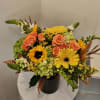 Orange roses and yellow gerbera daisies in a black vase