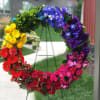 Rainbow floral wreath on a stand with roses, gerbera daisies, and purple blooms