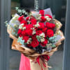 Bouquet of red roses with white filler flowers and eucalyptus in brown paper