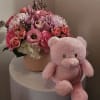 Pink flower arrangement in a round box with a pink teddy bear