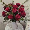 Bouquet of deep red roses in a white vase with airy greenery
