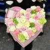 Heart-shaped pink box of pastel roses and carnations with a candle
