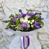 Purple and white bouquet wrapped in paper with a ribbon