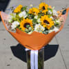 Bouquet of sunflowers and white flowers in orange wrap with a glass vase