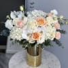 White and peach roses with orchids in a gold vase