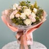 Bouquet of pale pink and white roses with small daisies wrapped in pink paper