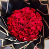 Round bouquet of red roses wrapped in black paper with gold trim