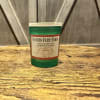 Green jar candle with an apple cinnamon label on a wooden surface