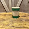 Green glass candle jar with a beige label on a wooden surface