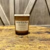 Brown jar candle with a beige label on a wooden surface