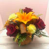 Bouquet of red roses, orange lily, and yellow carnations in a pumpkin container