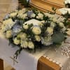 White floral casket spray with roses and hydrangeas