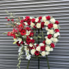 Heart-shaped red and white rose wreath on a stand