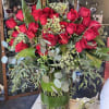 Large bouquet of red roses in a glass vase with greenery